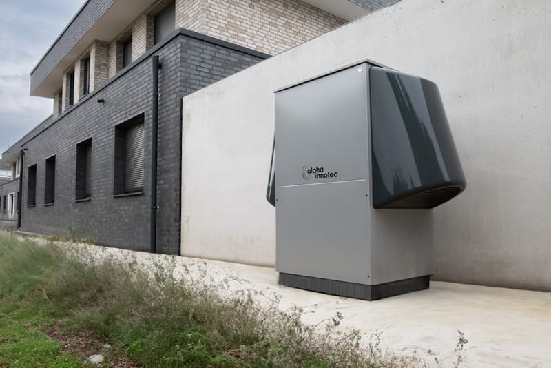Air-source heat pump outdoor unit installed against a residential home wall